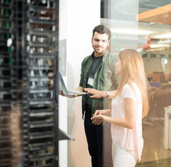 two business people standing server room with laptop discussing