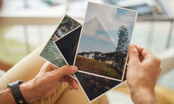 close up man holding photos with beautiful landscapes his hands
