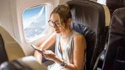 A lady with her phone inside the airplane