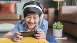 A boy wearing headphone and holding a phone