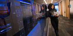 lady standing next to database holding a laptop