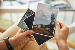 close up man holding photos with beautiful landscapes his hands