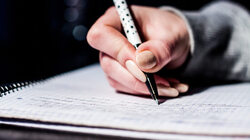 a hand holding a pen and writing somes notes