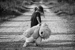 Boy walking away with teddy bear