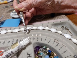 Senior woman holding a finding with tweezers as she makes jewelry