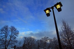 Illuminated light post in a winter park setting.