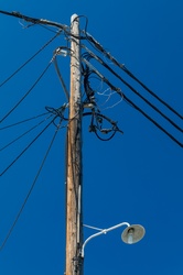 Wooden electric pole with wires against blue sky