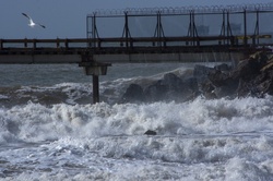 Stormy Pacific ocean crashing wave in front of a pier