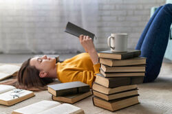 A woman lying down on the floor reading book