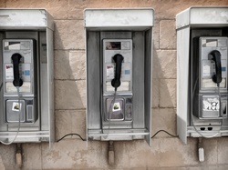 Three old telephone booths hanging on a wall