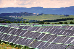 Solar power plant with wind turbines in the background