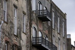 Side of an old weathered building with rot iron enclosed balconies