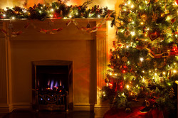Lit Christmas tree with a fireplace at night