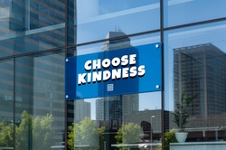 Blue sign with the request Choose Kindness on an office glass facade.