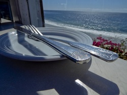 Fork and Knife on a white plate in front of a window looking out at the ocean