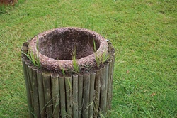 Container for garbage made with mortar and gravel surrounded by wooden poles