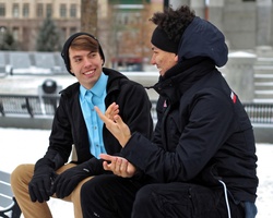 Two young lads chatting away on a park bench in winter
