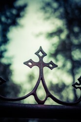 Rusted religious symbol in front of light sky.