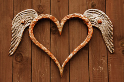 Rusty heart with wings on wooden background