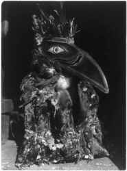 Dancer wearing raven mask with coat of cormorant skins.
