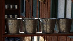 Rows Of Galvanized Buckets: Rows of galvanized buckets on wooden shelves with wooden shed in the background. Artistic effect applied.