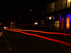 Slow shot of car at night moving past with long rear light shine