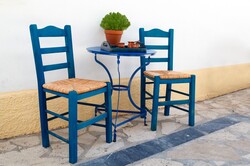 Greek traditional round shaped coffee table and blue chairs outside a cafe in Greece