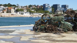 Crab traps pilled on pier with beach city in background
